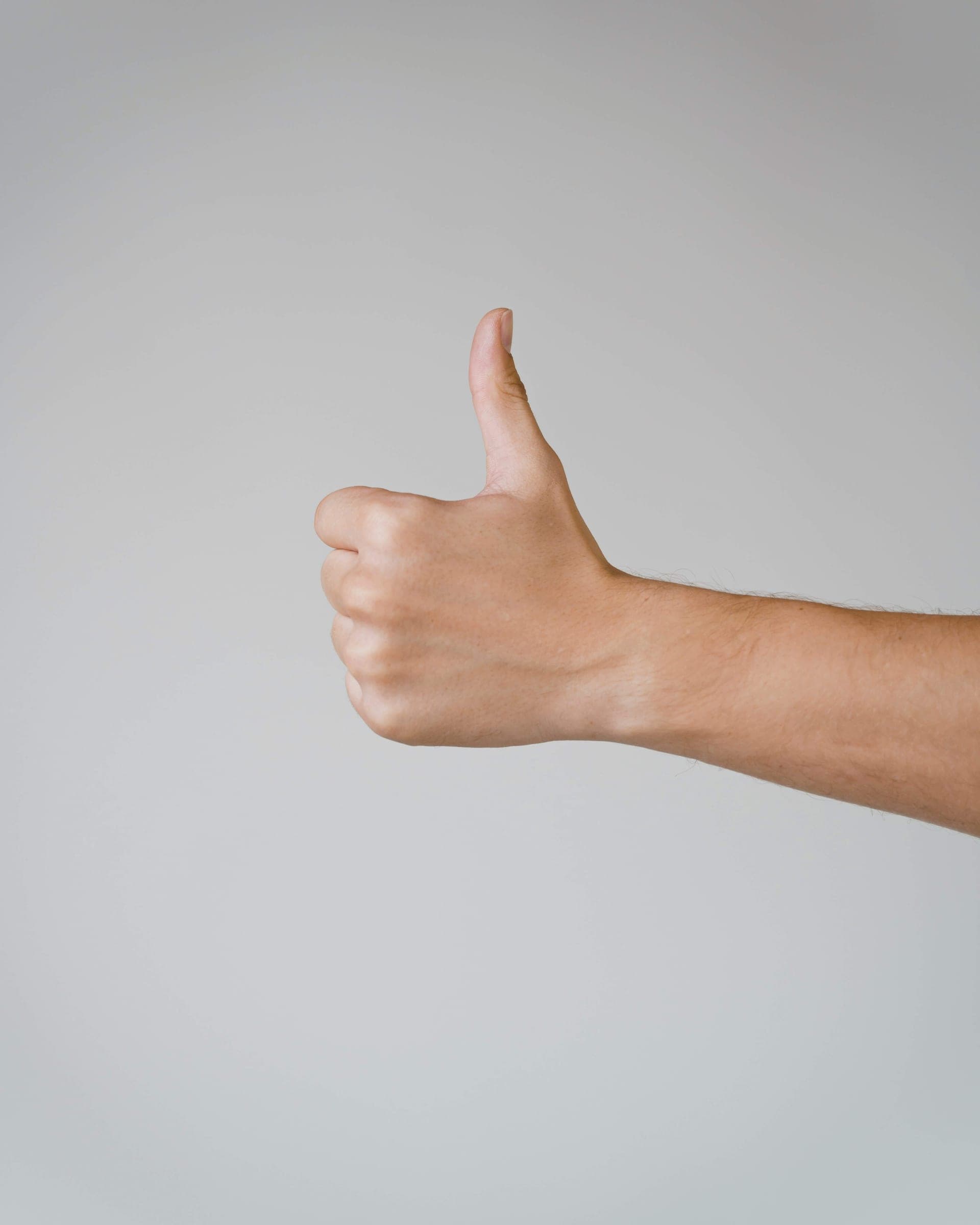 A thumbs-up against a calm gray backdrop.